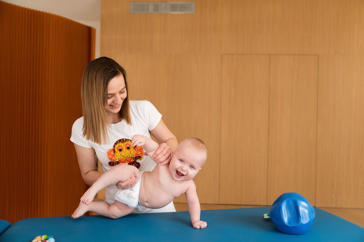 Fyzioterapeutka s usmievavým bábätkom počas terapie